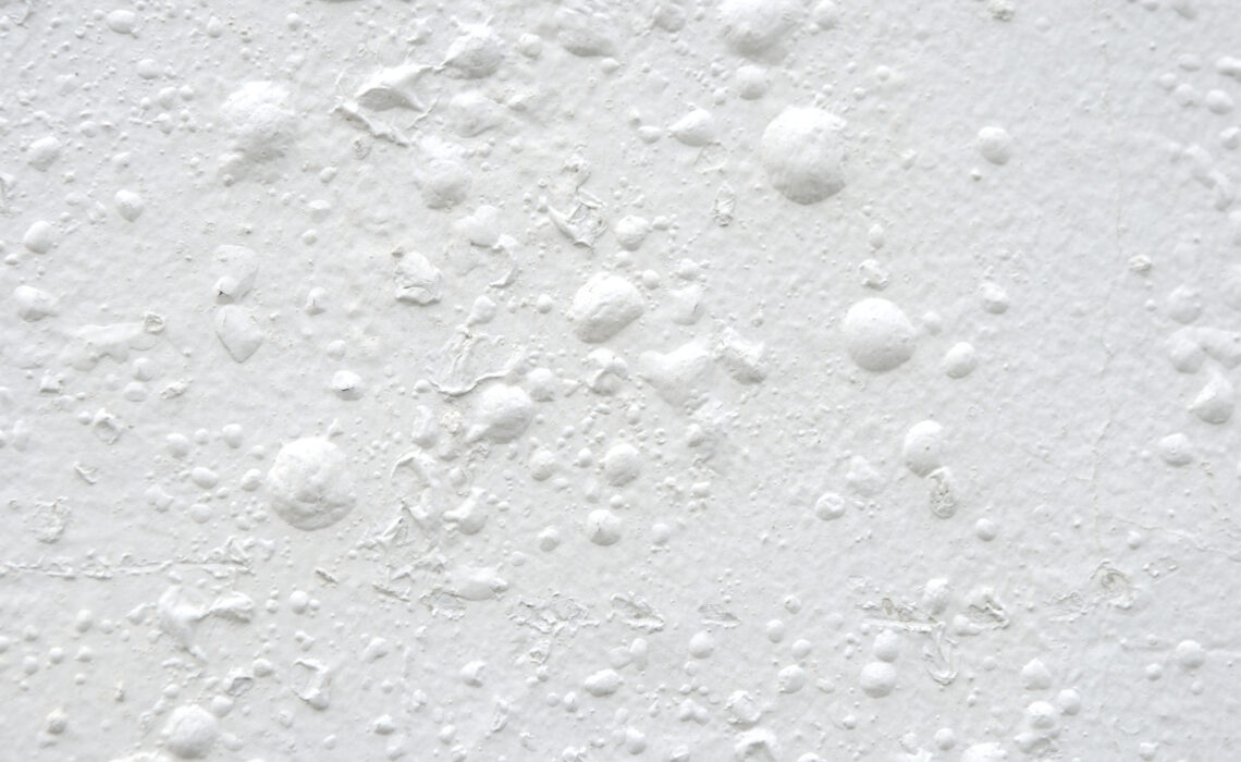 White wall with paint dried into crusty bubbles full frame textured background